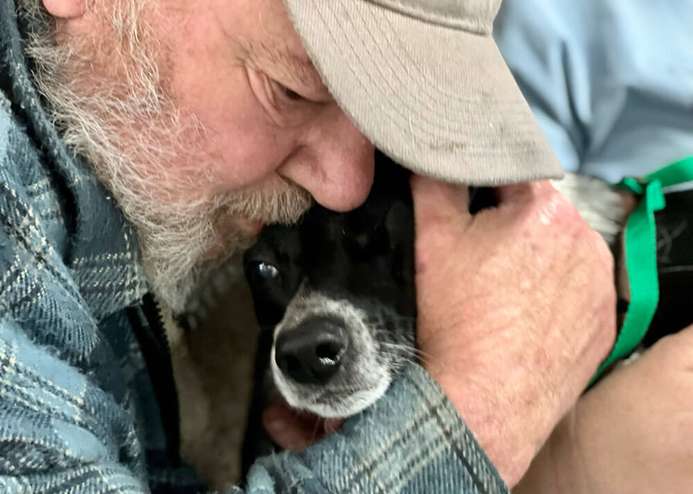 Close-up of an older man cuddling his dog.